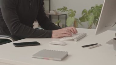 Modern ofiste bilgisayar başında çalışan, kulaklık ve gözlük takan, beyaz ırktan ciddi bir erkek programcının yavaş çekimleri.