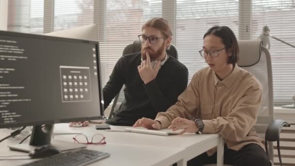 Medium Slowmo Skott Kaukasiska Och Asiatiska Programmerare Talar Medan Arbetar — Stockvideo