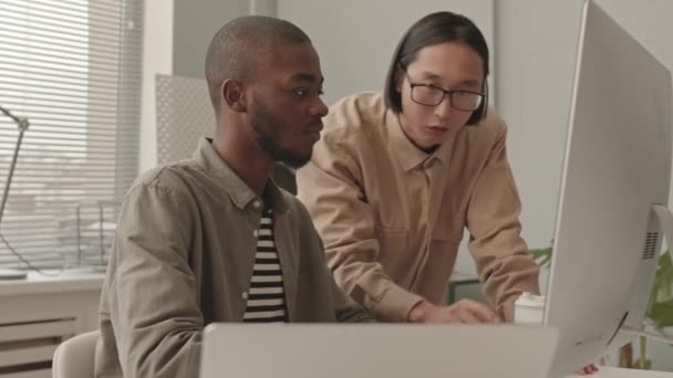 亚洲和非洲裔美国男性程序员合作开发现代办公室监视器软件的中档慢镜头 — 图库视频影像