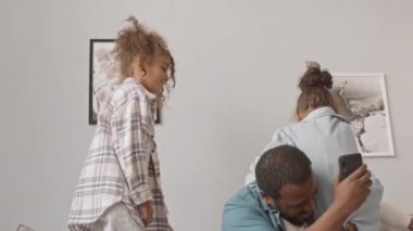Yavaş çekimde Afro-Amerikalı bir adam ve iki tatlı kızı rahat bir dairede kanepede birlikte eğleniyorlar. Babalarının omuzlarına tırmanmaya çalışan kızlar.