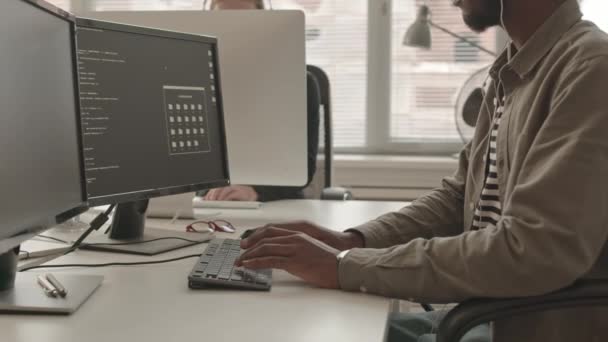 非洲裔美国男性程序员穿着便服和耳机在现代办公室电脑上编写程序代码的慢镜头 — 图库视频影像