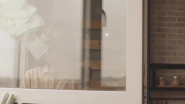 Genç Asyalı bir kadının evdeki camları bez kullanarak temizlerken ki yavaş çekimini çek.