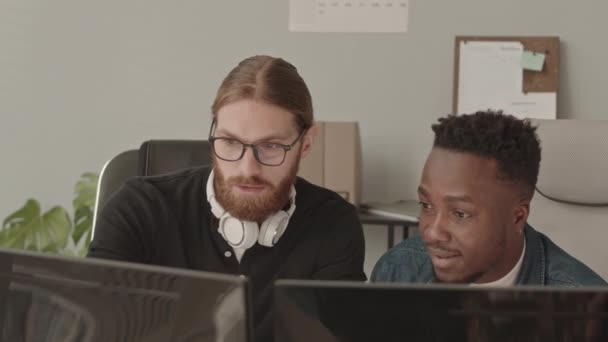 2人の若い白人とアフリカ系アメリカ人のIt専門家が プログラマー事務所でコンピュータモニタを見ているソフトウェアについて話し合った — ストック動画