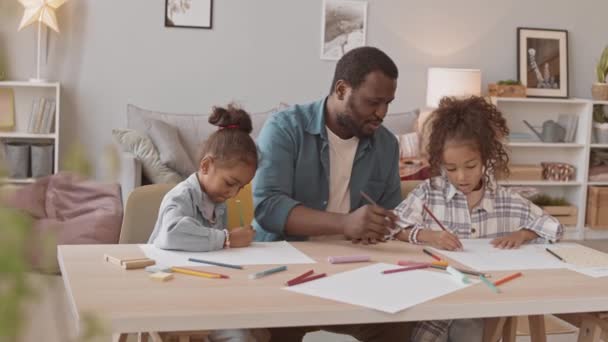 アフリカ系アメリカ人の男と彼の2人の小さな娘が一緒に居心地の良い家で時間を描いて話しています — ストック動画