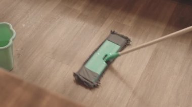 Evde yerleri paspasla temizleyen birinin yavaş yavaş yakın çekimi.