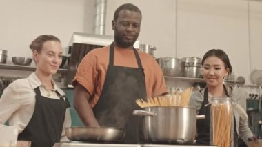 Afrika kökenli Amerikalı bir adamın, ocakta kaynar suyla spagettiyi tencereye koyması, Asyalı ve beyaz bir kadının mutfakta yan yana durması, genç bir kadın aşçının gelip izlemesi...