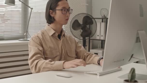 穿着眼镜在程序员办公室电脑上工作的亚洲年轻人的慢镜头 — 图库视频影像