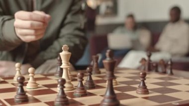 Üniversite kampüsünde satranç oynayan tanınmayan erkek öğrencinin yavaş yavaş yakın çekimi.