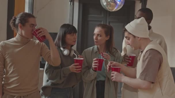 キャンパス内の学生パーティーで楽しみながら カメラで赤いカップを上げる5人の陽気な多民族大学の友人の中低速ショット — ストック動画