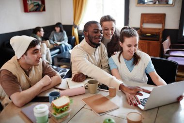 Öğrenciler masada dizüstü bilgisayar kullanıyorlar.