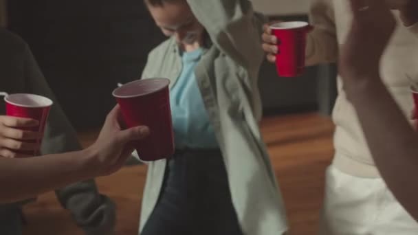 キャンパス内で行われたパーティーでは 使い捨ての赤いカップで乾杯する多様な大学生のグループの手によるスローショット — ストック動画