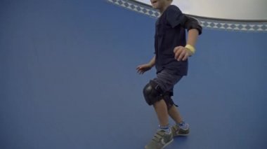 Aktif olarak 7 yaşındaki beyaz bir çocuğun kaykay pistinde mavi kaykay pistine tırmanırken görüntüsü.