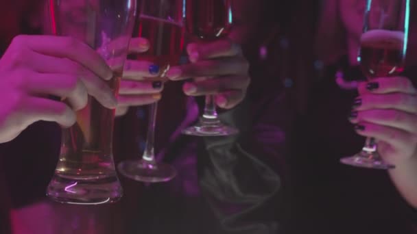 20代の男性と女性の多様なグループが ネオンライトのパーティーで一緒にクラブをしながらアルコール飲料でガラスをクリックしている間に 中程度のクローズアップ — ストック動画