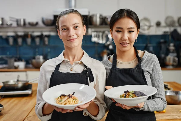 Camareras sosteniendo platos gourmet en la cocina — Foto de Stock
