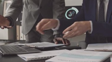 Masada oturan, proje belgeleriyle çalışan, gündüzleri bilgisayarı kullanan tanınmayan iki erkek yöneticinin düşük açılı görüntüsü.