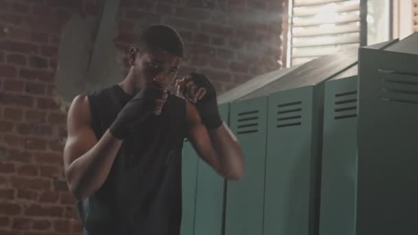 在拳击俱乐部更衣室里 专注的非裔美国男性拳击手双手包扎 双手朝天抛出一拳 慢镜头中的镜头 — 图库视频影像