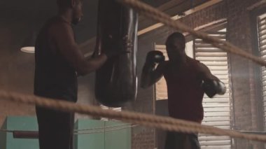 Boks kulübünde koçla boks yaparken, kaslı zencilerin boks torbalarını yavaş çekimleri.