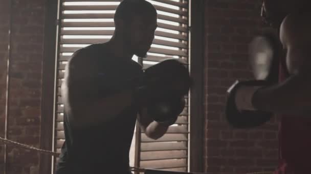 两名戴手套 头戴护垫 肌肉发达的黑人男子在拳击台上练习拳打脚踢时的中慢镜头 — 图库视频影像