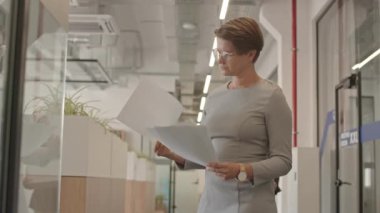 Modern ofis koridorunda duran ve yanından bir şeyler geçen yeni işvereni kağıt kutusuyla selamlayan adaylara bakan kadın işverenin orta yavaş çekimi.