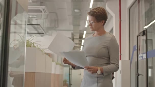 候補者を見ている女性雇用主の中低速ショット現代のオフィス廊下に立つCvは 通過するものと紙の箱で新しい雇用主を迎える — ストック動画