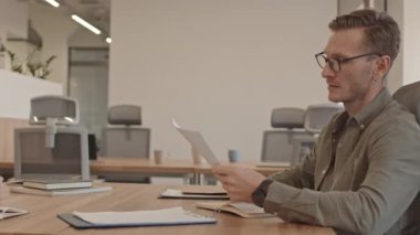 Hem işverenin hem de çalışanın, modern ofiste birbirlerinin önünde oturarak iş sözleşmesi imzalamasının yavaşlığıyla çekilen PAN yan görünüm belinde.