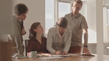 Bir grup çalışanın iş belgesine ya da kontratına imza atarak patronluk bürosunun masasında beklediği orta yavaş bir çekim.