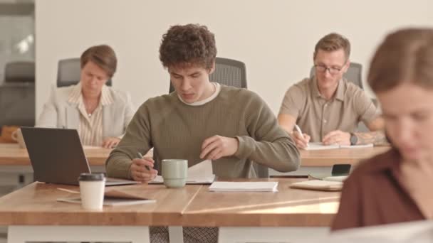 Средний Словмо Снимок Молодого Человека Подписывающего Бумаги Работающего Ноутбуке Сидя — стоковое видео