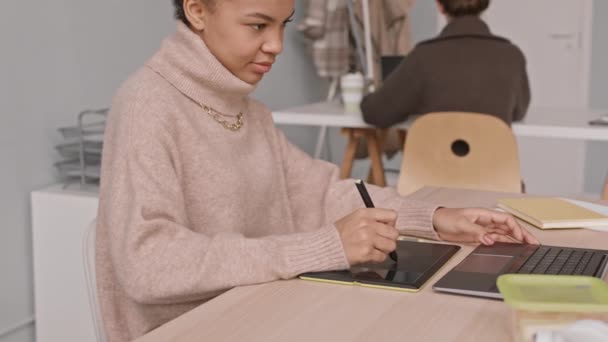 ウエストアップ遅いショットの若い女性デザイナー描画上のグラフィックタブレットでペン 座っているテーブルで現代オフィスと同僚 — ストック動画