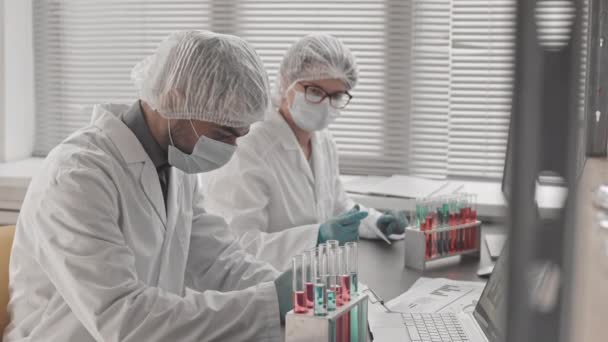 의료용 마스크를 착용하고 연구소 책상에 시험관에서 물질을 연구하는 — 비디오
