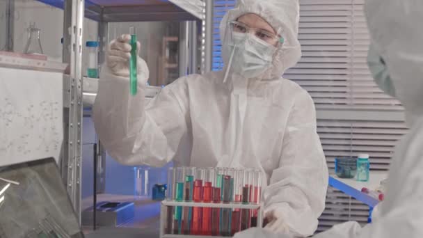 작업복을 고글을 마스크를 실험실에 시험관에서 물질을 분류하고 컴퓨터로 사람을 — 비디오