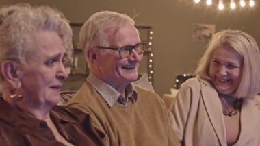 Oturma odasında kanepede oturup TV 'de film tartışırken birlikte eğlenen son sınıf öğrencilerinin orta ölçekli yakın çekimi.