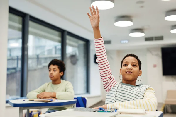 Ragazza alzando la mano in classe — Foto Stock
