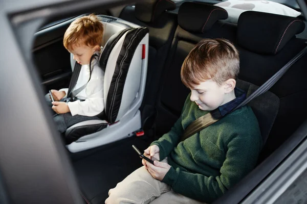 Jongens met behulp van telefoons in auto — Stockfoto