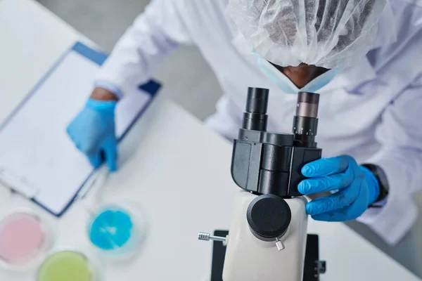 Scientist examining sample with microscope — Stock Photo, Image