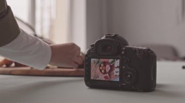Slowmo close up of unrecognizable food photographer creating composition of fresh bred with blue cheese, tomatoes and figs on wooden plate