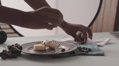 Slowmo closeup of unrecognizable Black female photographer plating delicious blueberry cheese pancakes before taking photos of them on digital camera