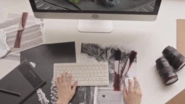 Top view shot of hands of unrecognizable female photographer editing photo on computer using mouse and keyboard