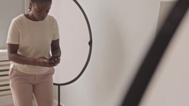 Tilting shot of African-American female food blogger taking pictures of delicious blueberry cheese pancakes for breakfast on smartphone