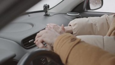 Slowmo shot of young affectionate couple holding their hands over hot air outlet in car, warming up on cold winter day during road trip