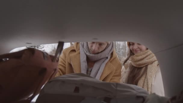 Medium Slowmo Shot Young Caucasian Couple Winterwear Taking Backpacks Out — стоковое видео