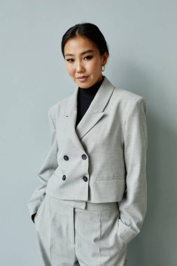 Güzel Asyalı iş kadınının dikey bel portresi. Takım elbise giymiş ve kameraya bakıyor.