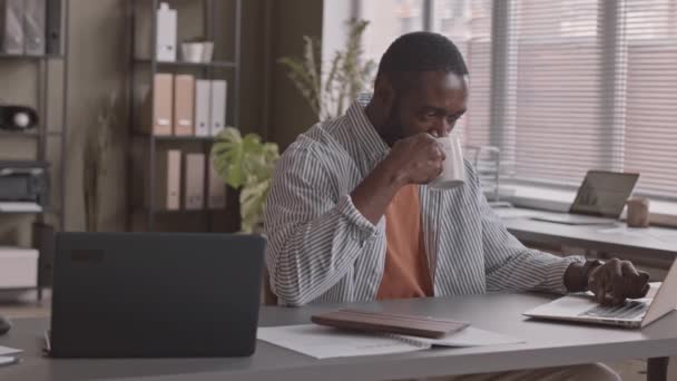 Medellångsam Bild Afroamerikansk Affärsman Dricka Kaffe Och Sms Bärbar Dator — Stockvideo