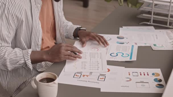 アフリカ系アメリカ人の男性財務会計士がオフィスのワークデスクでノートパソコンの前に座ってビジネスグラフや図を分析 — ストック動画