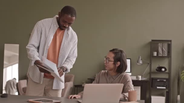 近代的なオフィスで働く2人の若い多民族の男性のスローショットは ビジネス文書についての議論を持っています — ストック動画