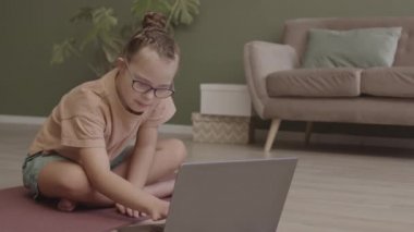 Nilüfer çiçeği pozunda meditasyon yapan 11 yaşındaki kızın yoga dersinde evden bilgisayarla gözlerini kapattığı ağır çekim.