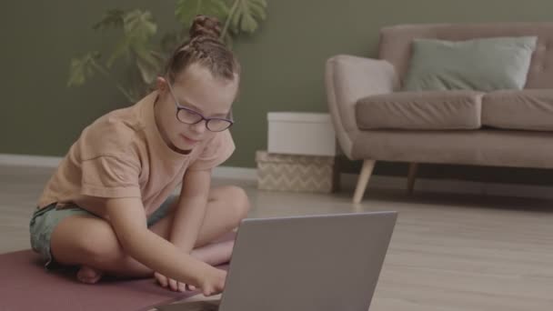 在家庭笔记本电脑上的在线瑜伽课上 11岁的女孩在荷花姿势中打坐 眼睛闭着 慢镜头 — 图库视频影像