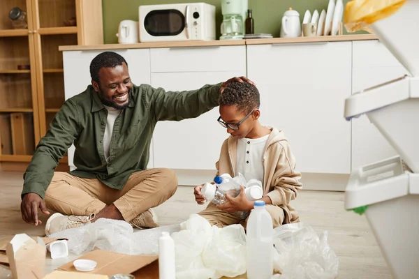 Lachende vader en zoon Sorteren Plastic thuis — Stockfoto