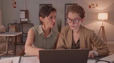 Yetişkin kadın ve genç bayan öğretmenin bireysel ders sırasında laptopta sunuma baktığı yavaş çekim belini kaldır.