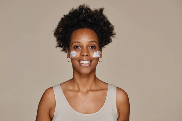 Sonriente mujer negra con crema facial mínima — Foto de Stock