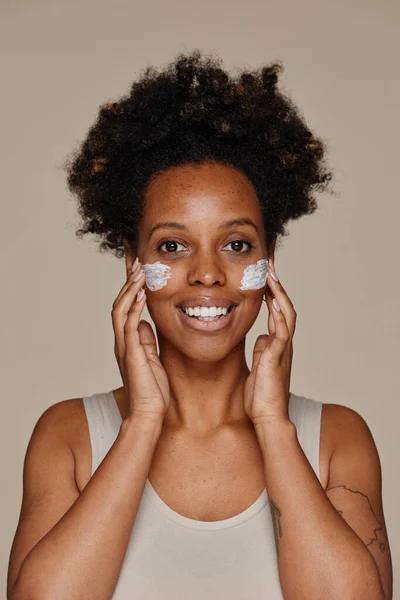 Sonriente mujer negra con crema facial — Foto de Stock